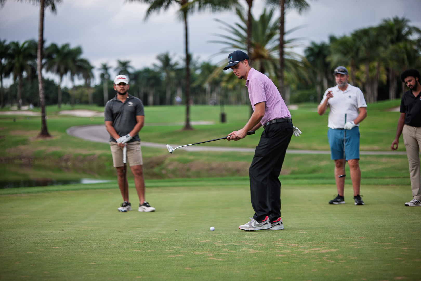 Golfer mid-putt with group watching
