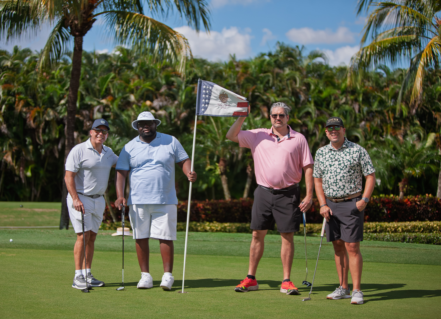 Foursome posing with pin flag
